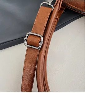 Detail of brown litchi pattern leather strap with adjustable dark grey metal buckle