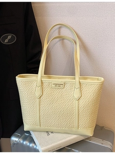 Sac fourre-tout tissé jaune pâle sur une valise, sac à épaule élégant pour le bureau