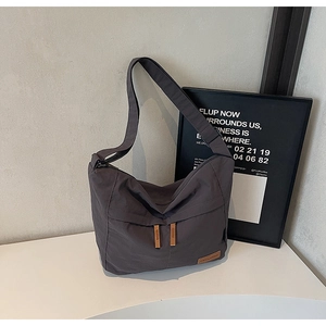 Detail view of dark grey canvas tote with brown leather zippers and logo patch