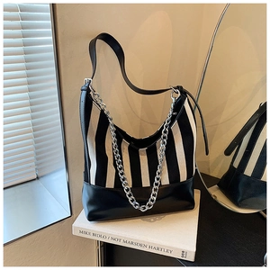Detail of striped canvas shoulder bag with black leather base and dual chain strap