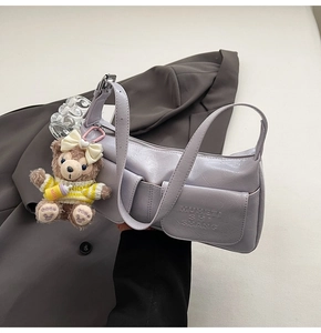 Close-up of lilac baguette bag with pleated texture and cute plush bear charm detail