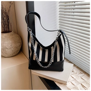 Detail of a striped canvas and leather shoulder bag with decorative silver chain link