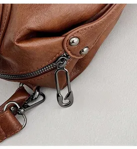 Detail of vintage brown leather bag with black metal safety pin zipper and rivets