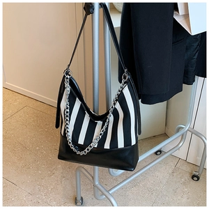 Detail of striped canvas shoulder bag with silver chain and faux leather base on a hanger