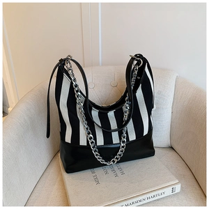Close-up of black and white striped tote bag with silver chain and leather strap
