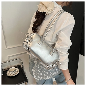 Detail of silver metallic handbag featuring large metal eyelets and lacing design