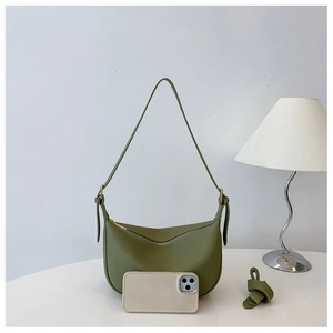 Detail view of grass green crescent saddle bag with pebbled leather texture and knot strap