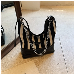 Detail of black and white striped canvas hobo bag with silver chain and leather strap