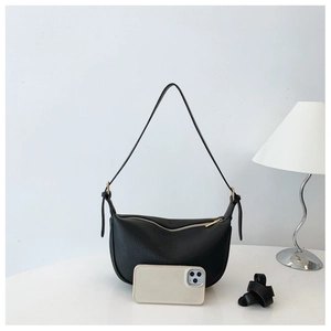 Detail of black lychee grain saddle bag with gold zipper and smartphone for scale
