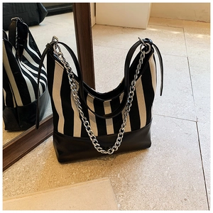 Detail of black and white striped tote bag with silver chain strap and leather handle