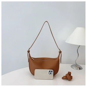 Detailed view of brown lychee leather saddle bag shown with phone for size reference