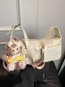 Cream shoulder bag with glossy crinkle texture and cute plush charm in lifestyle setting