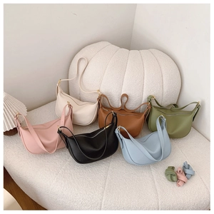 Close-up of hobo shoulder bags in six colors with litchi grain texture on a soft sofa