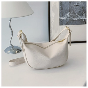 Detailed macro view of cream half-moon bag featuring lychee texture and gold zipper