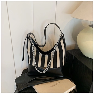 Detail of black and white striped shoulder bag with silver metal chain on leather jacket