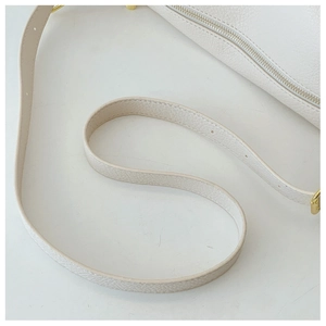 Detail of off-white lychee grain leather bag with zipper and gold-tone metal hardware