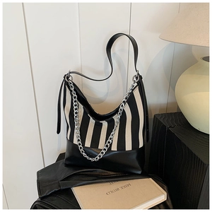 Detail of striped canvas tote bag with black leather trim and silver chain decoration