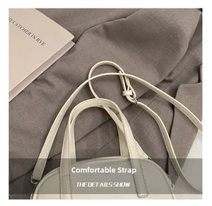 Vue détaillée du sac en cuir crème montrant les doubles poignées et la bandoulière