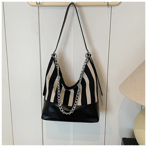 Detail of black and white striped canvas tote with leather base and silver chain strap
