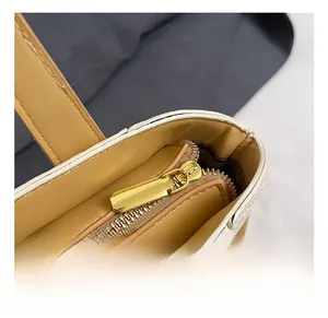Gros plan sur la fermeture éclair en métal doré et la texture cuir du sac seau