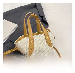 Détail d'un sac à main tissé avec lanières marron clair sur un fond de costume moderne