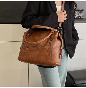 Brown vintage faux leather tote bag worn as a crossbody by model in black suit