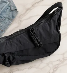 Detailed close-up of a black nylon crossbody bag with dual smooth zipper pulls
