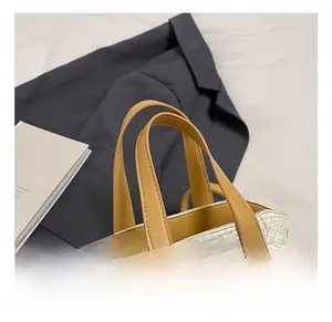 Gros plan du sac seau tressé blanc avec poignées en cuir marron et rivets dorés