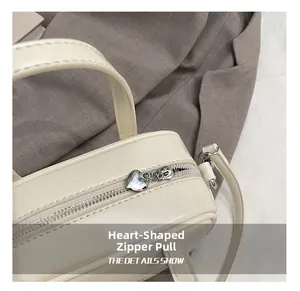 Détail de la fermeture éclair en forme de cœur argenté sur un sac carré blanc