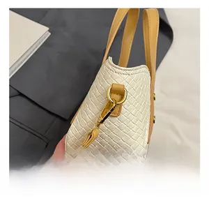 Gros plan détaillé des crochets métalliques dorés sur un sac seau blanc tressé