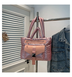 Dettaglio della borsa imbottita in nylon rosa lucido con tasche a fibbia e manici morbidi