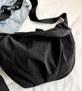 Detail view of the black nylon dumpling bag featuring an adjustable wide woven strap