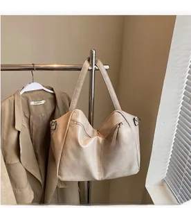 Close-up of minimalist cream large tote bag with zipper detail on metal stand