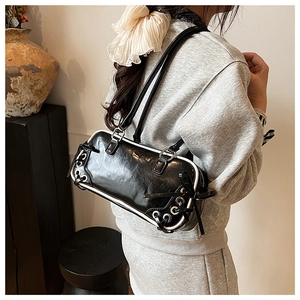 Detail of black glossy handbag featuring white contrast piping and ribbon drawstring bow