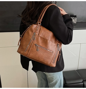 Detail of vintage brown soft leather tote bag with functional zippers and silver hardware