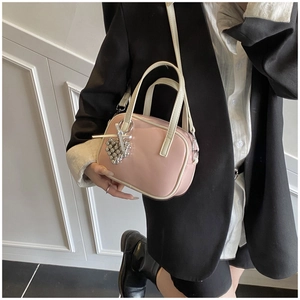 Petit sac en cuir verni rose avec poignées blanches et breloque cœur sur veste noire