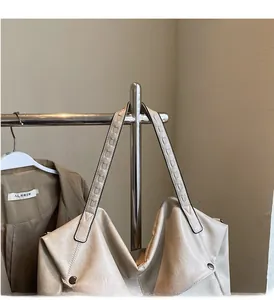 Detail of the woven handle and soft cream leather texture on this large tote bag