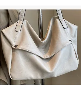 Detail of off-white tote bag with soft leather texture and stylish metal rivet accents