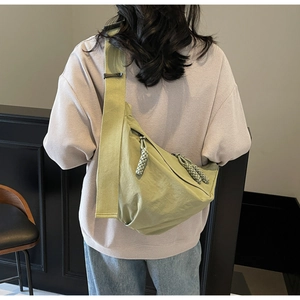 Close-up of a mint green nylon crescent bag on model showing back view and wide strap