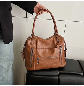 Detail of vintage brown leather tote bag with clip-shaped zippers and metal rivet hardware