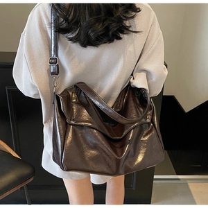 Model wearing a large chocolate oil wax leather tote bag with glossy finish and silver hardware
