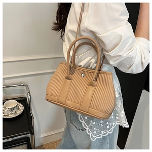 Detail of tan pleated leather bucket bag with silver metal buckle and round handle