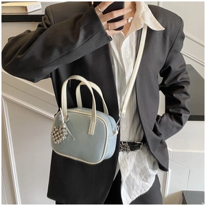 Détail du sac à main bleu clair verni avec bordure crème et pendentif cœur perlé