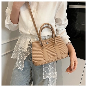 Detailed view of khaki bucket bag with vertical pleated texture and silver hardware accents