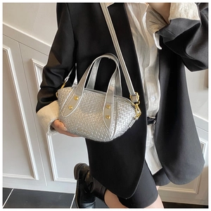 Sac seau tressé argenté avec reflets métalliques et clous dorés porté par un mannequin