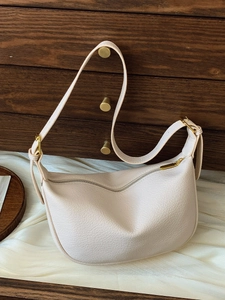 Chic cream crescent shoulder bag with pebbled leather texture and gold hardware details