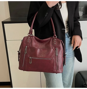 Dettaglio borsa in pelle bordeaux con cerniere multiple in argento e borchie lucide