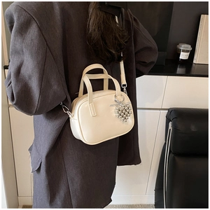 Modèle portant un mini sac bandoulière beige avec breloque cœur argentée et finitions