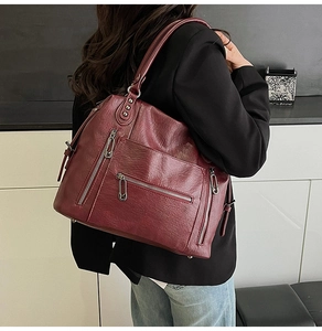 Detail of dark wine red PU leather tote bag with multi-zipper pockets and rivet decor