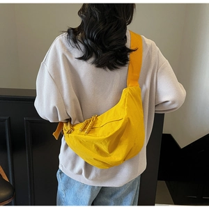 Detail of a bright yellow crescent nylon crossbody bag with woven zipper and wide strap